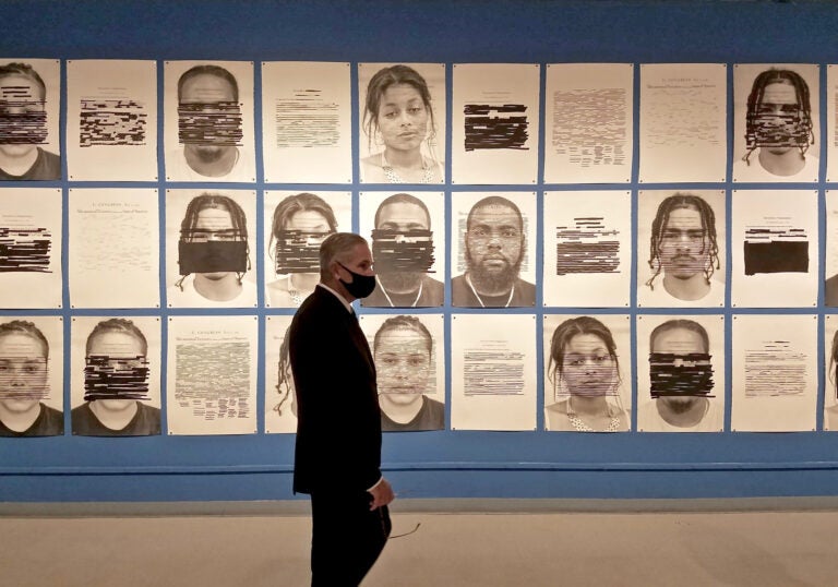 District Attorney Larry Krasner views 'Redaction,' a mural of portraits by Titus Kaphar and Reginald Dwayne Betts in the gallery of the African American Museum of Philadelphia