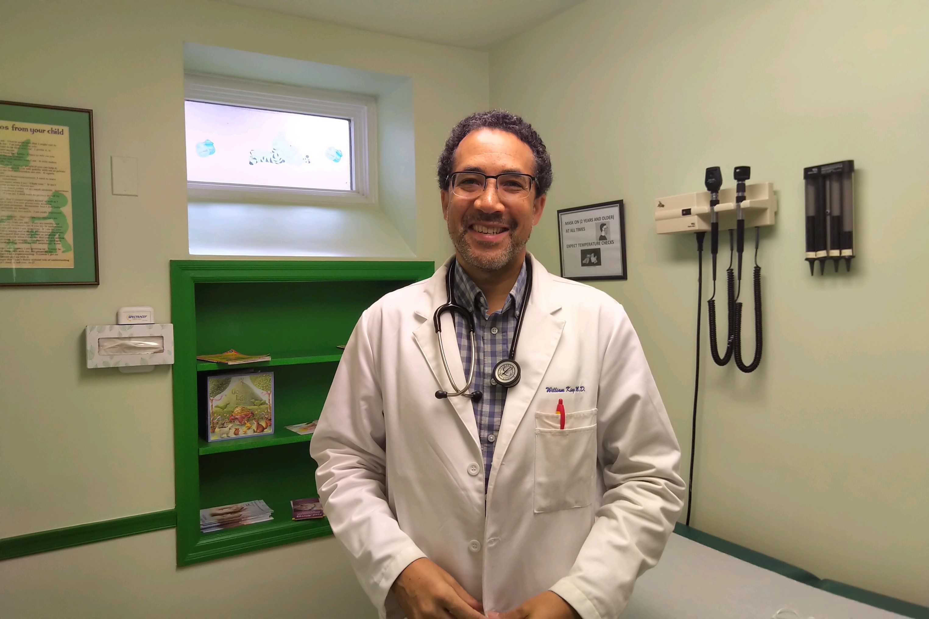 Dr. William King, a Black men, wearing a lab coat in his office.