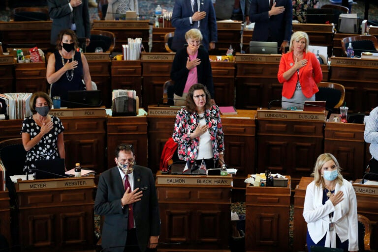 In this Wednesday, June 3, 2020 file photo, State Representatives stand at their desks during the Pledge of Allegiance in the Iowa House chambers, at the Statehouse in Des Moines, Iowa. (AP Photo/Charlie Neibergall)