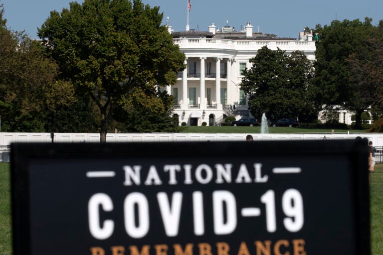 The White House is seen in the background as sign of the National COVID-19 Remembrance, event at The Ellipse outside of the White House, Sunday, Oct. 4, 2020, in Washington. (AP Photo/Jose Luis Magana)