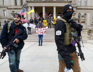 In this April 15, 2020 file photo, protesters carry rifles near the steps of the Michigan State Capitol building in Lansing, Mich. (AP Photo/Paul Sancya)