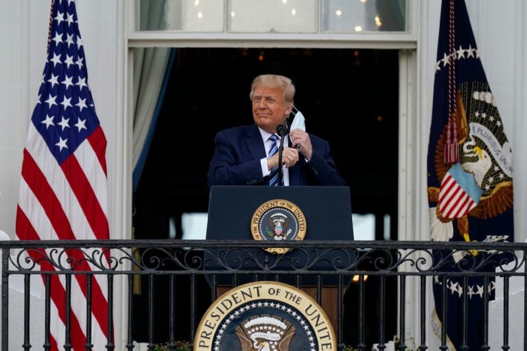 President Donald Trump removes his face mask to speak from the Blue Room Balcony of the White House to a crowd of supporters, Saturday, Oct. 10, 2020, in Washington. (AP Photo/Alex Brandon)