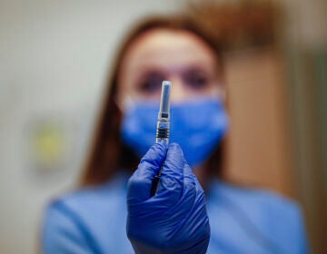 A health worker holding a COVID-19 vaccine vial