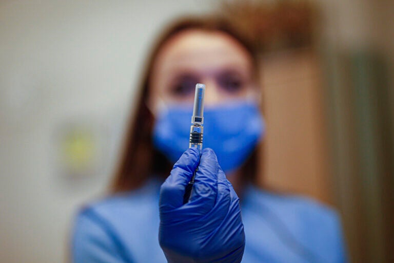 A health worker holding a COVID-19 vaccine vial