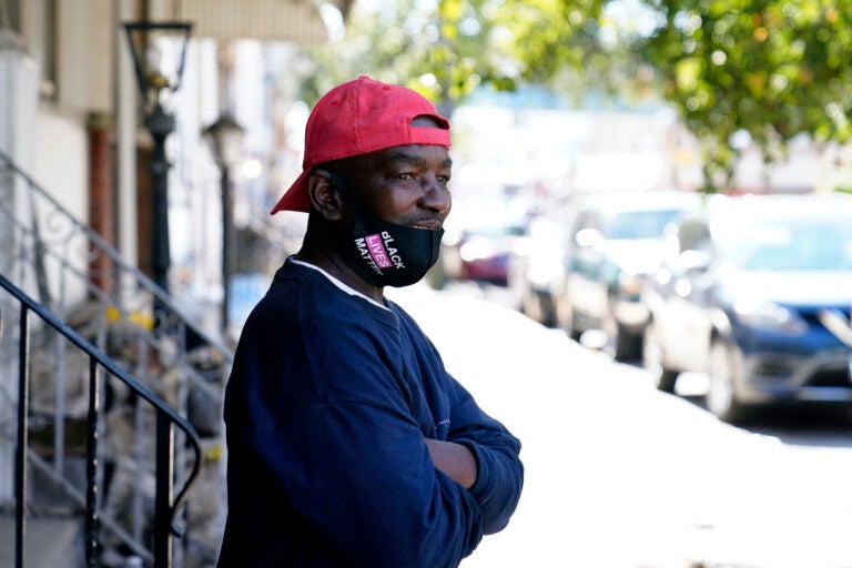 Black man standing on West Philadelphia face mask donning a face mask