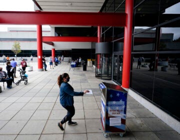 A woman drops off her ballot for the 2020 General Election outside the Chester County Government Services Center, Friday, Oct. 23, 2020, in West Chester, Pa. (AP Photo/Matt Slocum)