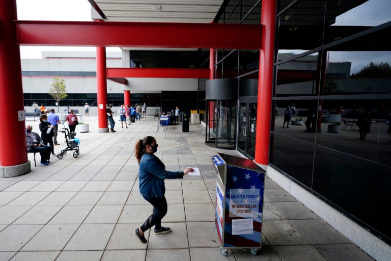 A woman drops off her ballot for the 2020 General Election outside the Chester County Government Services Center, Friday, Oct. 23, 2020, in West Chester, Pa. (AP Photo/Matt Slocum)