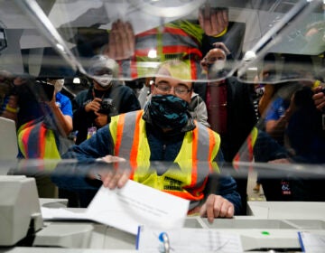 John Hansberry demonstrates an extraction machine at the city's mail-in ballot sorting and counting center