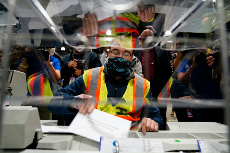 John Hansberry demonstrates an extraction machine at the city's mail-in ballot sorting and counting center