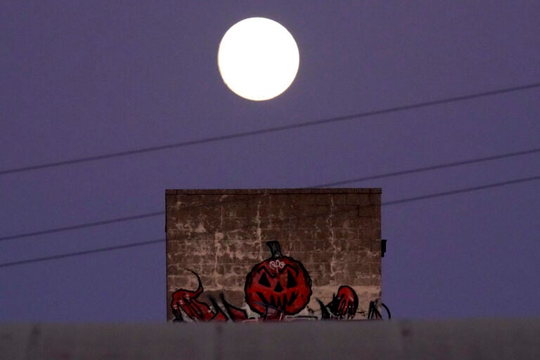 The nearly full moon rises beyond Halloween artwork painted on a building Thursday, Oct. 29, 2020, in Kansas City, Mo. (AP Photo/Charlie Riedel)