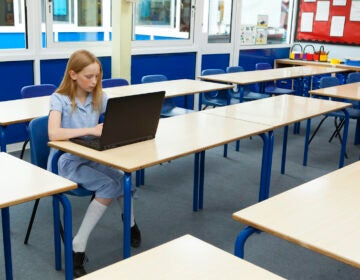 A student uses a laptop in an empty classroom.