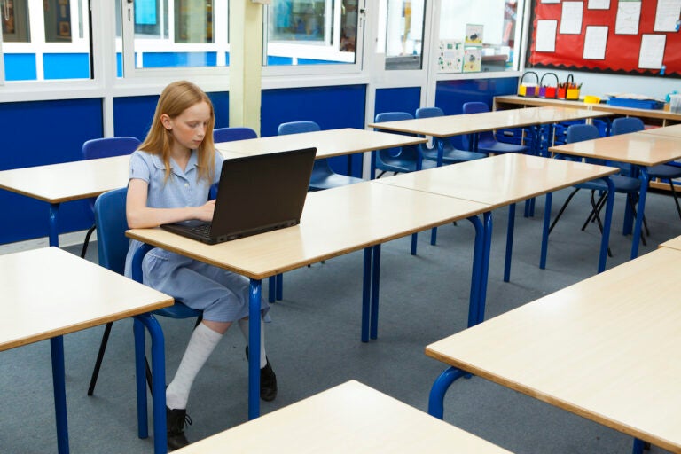 A student uses a laptop in an empty classroom.