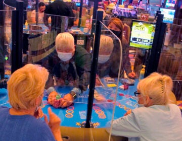 See-through barriers separate gamblers and a dealer at a card table at the Hard Rock casino