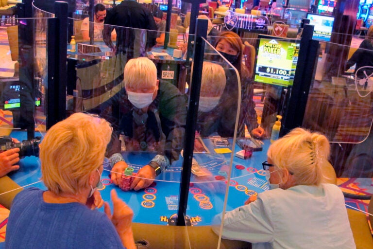 See-through barriers separate gamblers and a dealer at a card table at the Hard Rock casino
