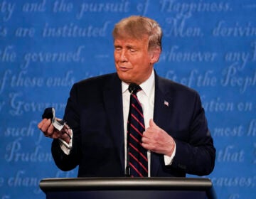 President Donald Trump holds out his face mask during the first presidential debate