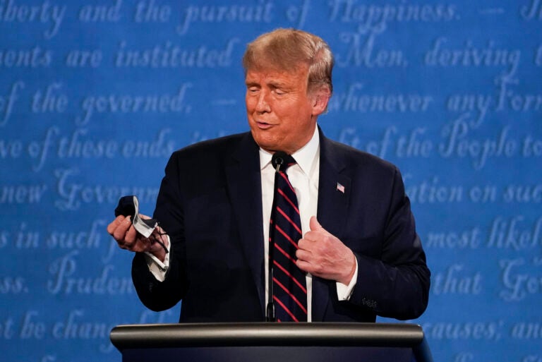 President Donald Trump holds out his face mask during the first presidential debate