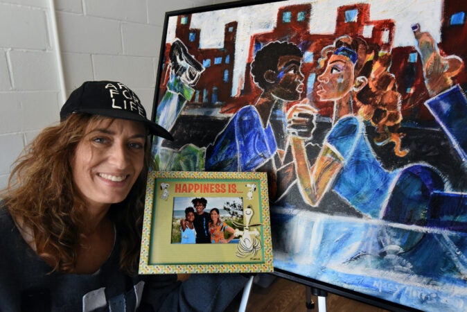 Art teacher Marcy Morris poses with a photograph of her own children and one of her works named 