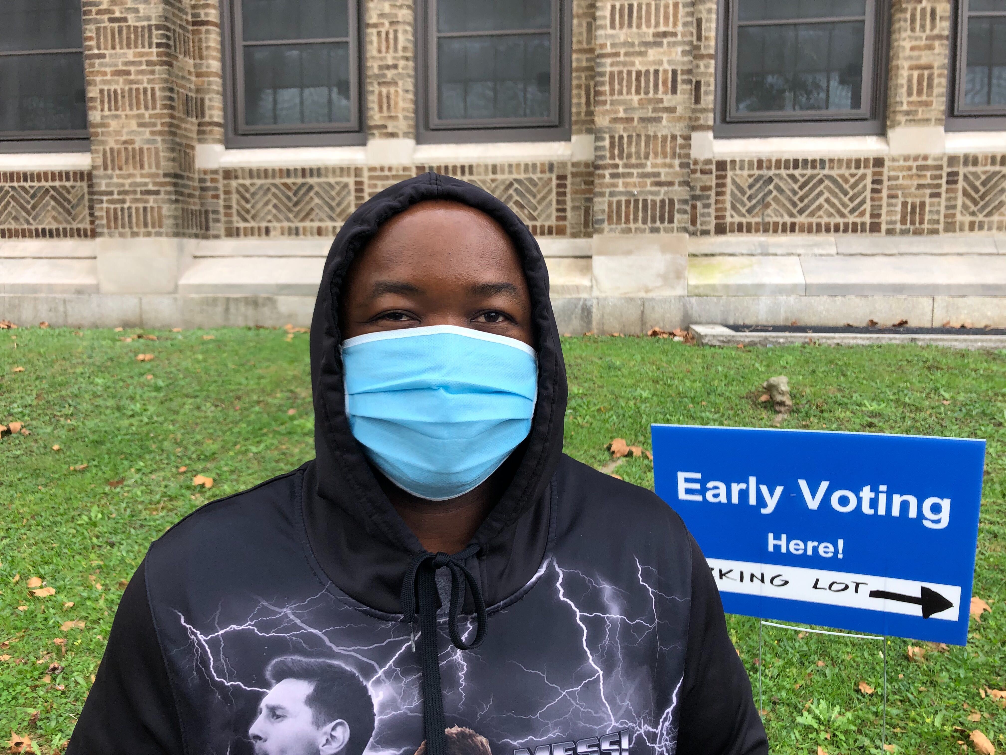 Man in a black hoodie, wearing a face mask, waits to vote.