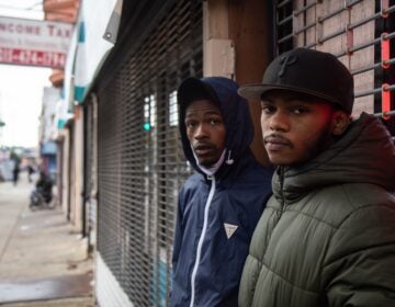 Two young Black men standing in front of a storefront.