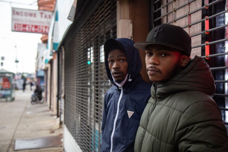 Two young Black men standing in front of a storefront.