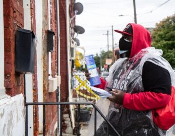 Briheem Douglas, a union maintenance worker at Lincoln Financial Field, knocks on doors in Philadelphia’s Kensington neighborhood to encourage people to make a plan to vote as soon as possible. (Kimberly Paynter/WHYY)