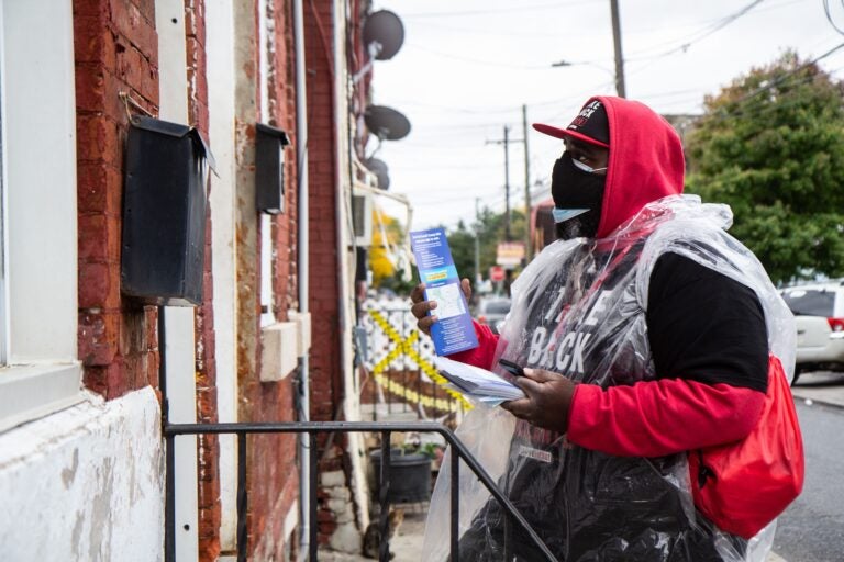 Briheem Douglas, a union maintenance worker at Lincoln Financial Field, knocks on doors in Philadelphia’s Kensington neighborhood to encourage people to make a plan to vote as soon as possible. (Kimberly Paynter/WHYY)