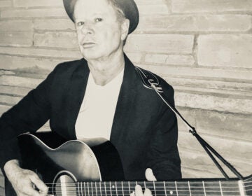Black and white photo of musician Jimmy McFadden holding a guitar