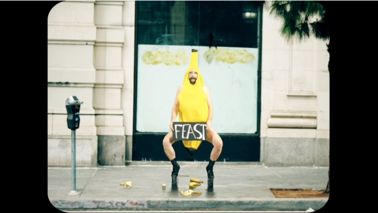A person in a banana costume holding a sign that says 