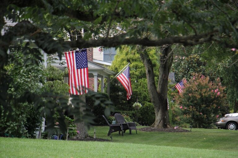 Flags fly from suburban homes in Moorestown, N.J.. (Emma Lee/WHYY)