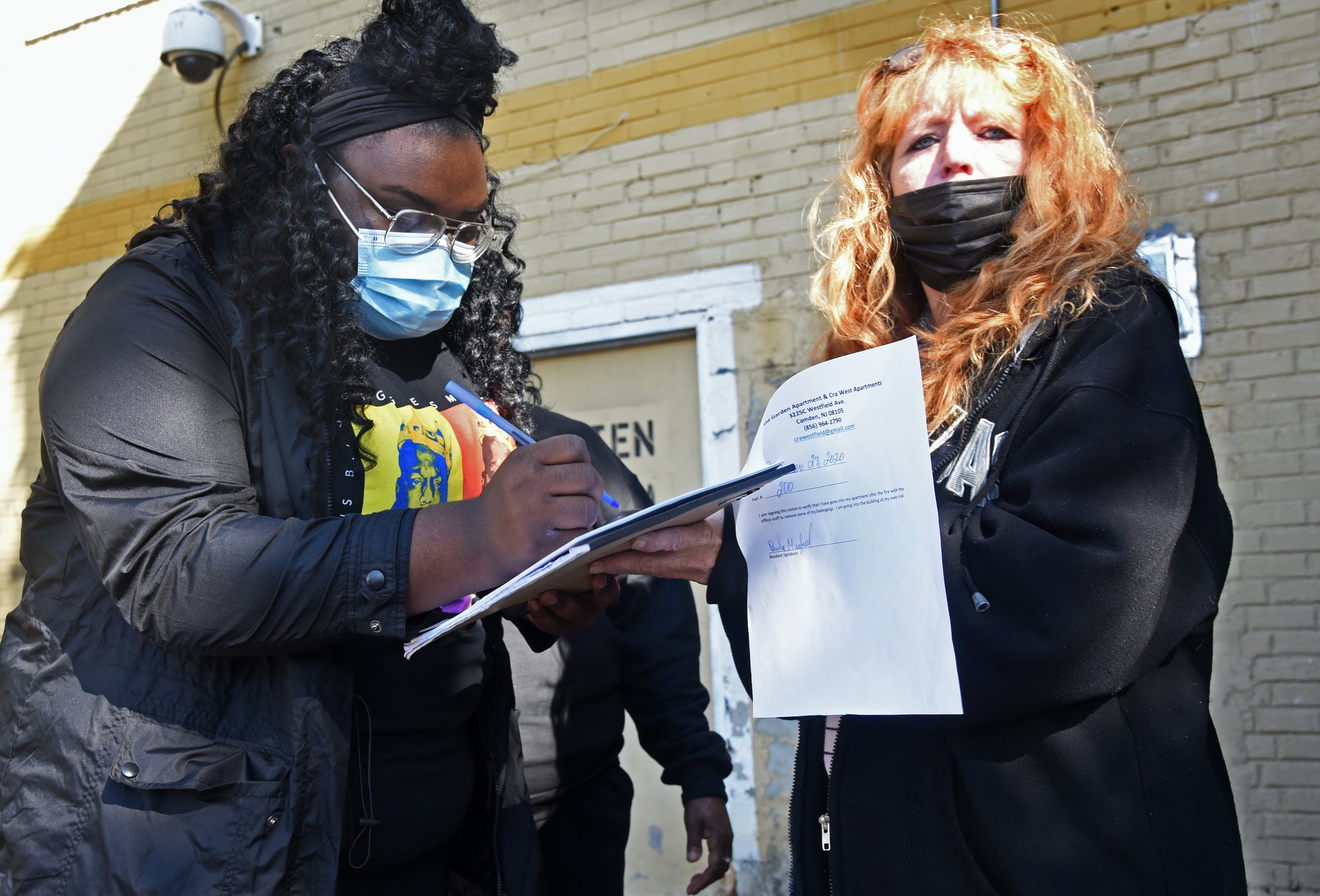 Renant Jessica Lynn signs a document allowing her to retrieve belongings from the apartment she shared with her mother; at right is property manager Gidget Bower