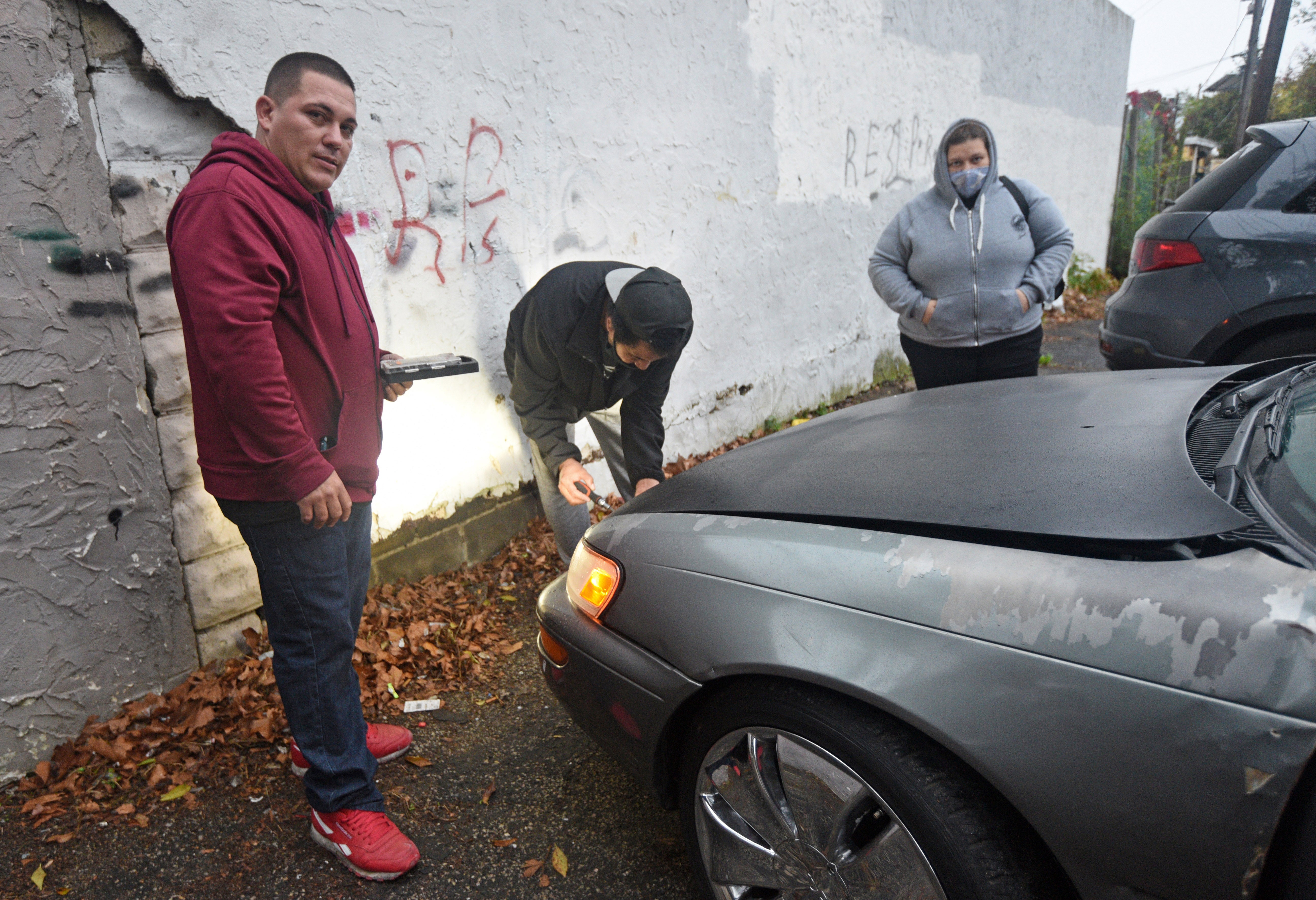 At the Cra-West Apartments in Camden on Oct. 26, tenant Juan Cruz Cardona (left) sells his Toyota Corolla for $1,000 because he needed the cash after the Oct. 25 fire gutted the building, forcing him to move.