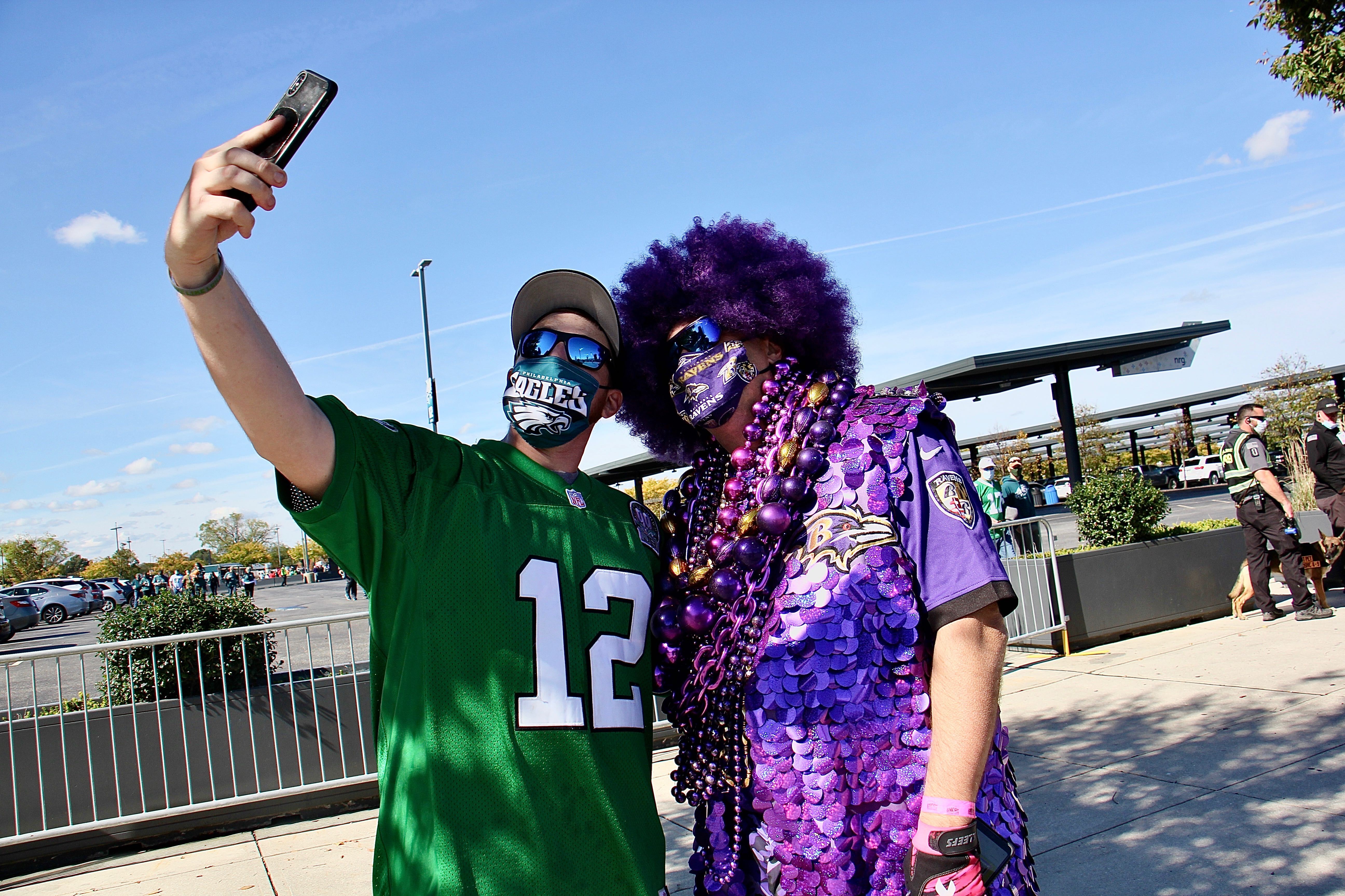 Eagles fan Mike Harbeson stops to take a selfie with elaborately costumed Ravens fan Ken Mioduski