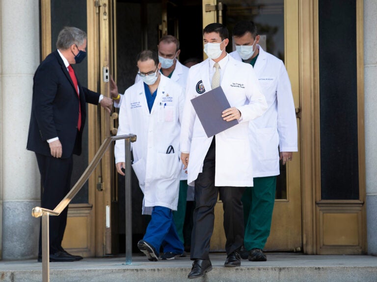 White House chief of staff Mark Meadows holds the door for Dr. Sean Conley and other members of the president's medical team on Sunday. Another update on Trump's condition is expected sometime on Monday.