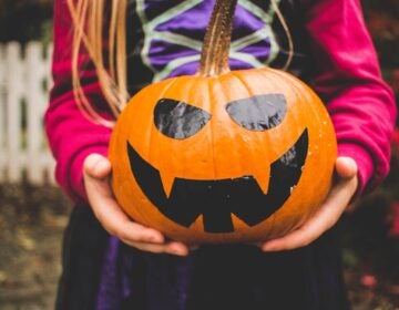 Girl in costume holding a pumpkin