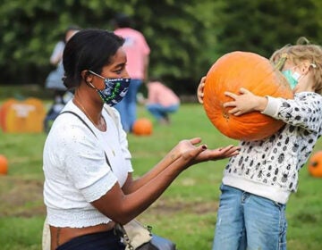 A woman and child at a pumpkin patch wearing masks