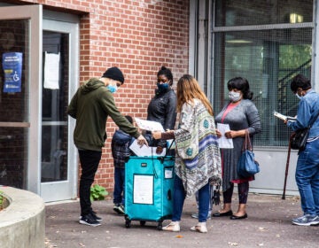 A voter drops a ballot in the box at the Julia De Burgos satellite election office. (Kimberly Paynter/WHYY)