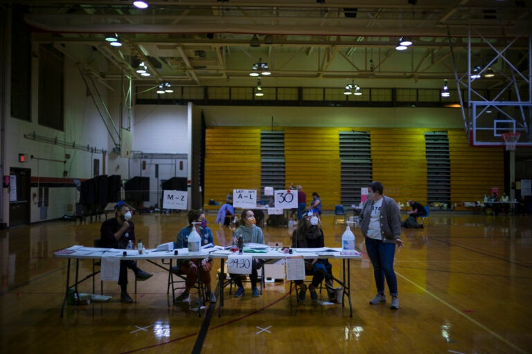 First-time election workers, seated, from left to right,  Chris DiStasi, Kaitlin Irvine, Alicia Dlugos and Katie Phillips, end their day at South Philadelphia High School, a polling site on South Broad Street. (Alan Chin for WHYY)