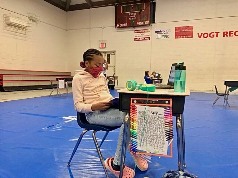 Faith Allen, 10, reads at her desk in Vogt access center gymnasium. (Emily Rizzo/WHYY)