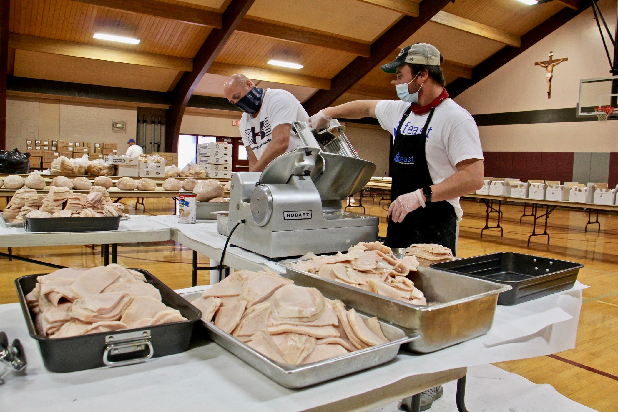 FEAST volunteers Rich Hutton (left) and John Morgan Clauss slice turkey breasts in the gymnasium at St. Robert Bellarmine Church