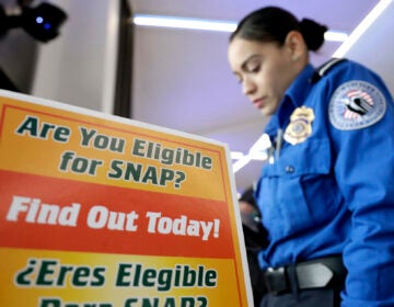 A Transportation Security Administration employee stands at a booth to learn about a food stamp program at a food drive at Newark Liberty International Airport to help government employees who are working without pay during the partial government shutdown, Wednesday, Jan. 23, 2019, in Newark, N.J. (AP Photo/Julio Cortez)