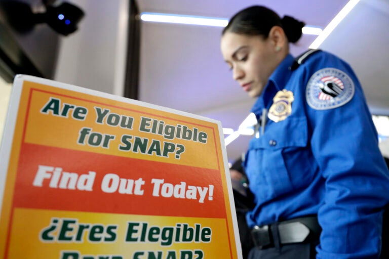 A Transportation Security Administration employee stands at a booth to learn about a food stamp program at a food drive at Newark Liberty International Airport to help government employees who are working without pay during the partial government shutdown, Wednesday, Jan. 23, 2019, in Newark, N.J. (AP Photo/Julio Cortez)