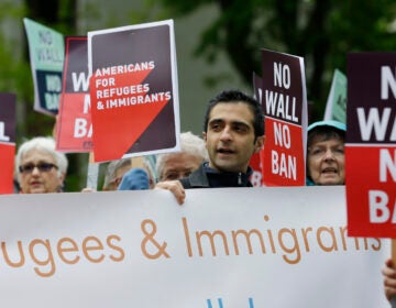 FILE - In this May 15, 2017, file photo, protesters hold signs during a demonstration against President Donald Trump's revised travel ban, outside a federal courthouse in Seattle.  Refugee advocates, including faith-based groups that President Donald Trump is courting in his re-election bid, called on Congress Thursday, Oct. 1, 2020, to halt his administration’s plans to slash the limit on refugees allowed into the U.S. to a record low, saying it goes against America’s values.    (AP Photo/Ted S. Warren, File)