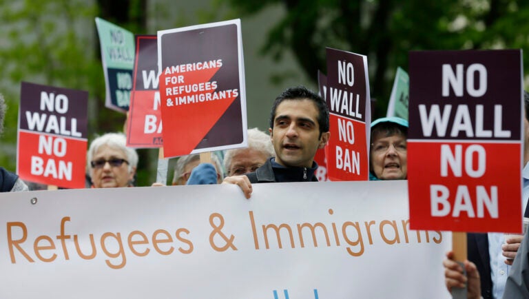 FILE - In this May 15, 2017, file photo, protesters hold signs during a demonstration against President Donald Trump's revised travel ban, outside a federal courthouse in Seattle.  Refugee advocates, including faith-based groups that President Donald Trump is courting in his re-election bid, called on Congress Thursday, Oct. 1, 2020, to halt his administration’s plans to slash the limit on refugees allowed into the U.S. to a record low, saying it goes against America’s values.    (AP Photo/Ted S. Warren, File)