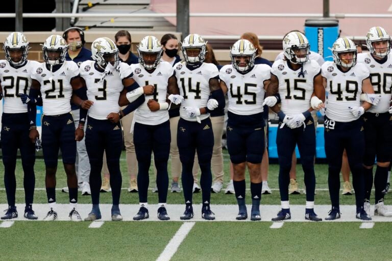 Georgia Tech players link arms before an NCAA college football game against Boston College as part of the Atlantic Coast Conference's first Unity Week, Saturday, Oct. 24, 2020, in Boston. (AP Photo/Michael Dwyer)