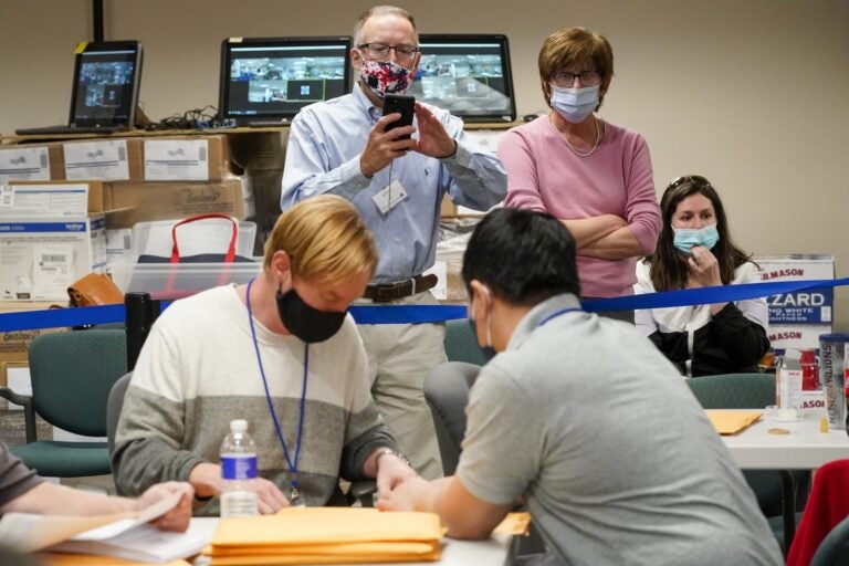 Republican canvas observer Ed White, center, and Democratic canvas observer Janne Kelhart, watch as Lehigh County workers count ballots as vote counting in the general election continues, Friday, Nov. 6, 2020, in Allentown, Pa. (Mary Altaffer/AP Photo)