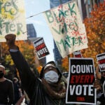 Zhanon Morales, 30, of Philadelphia, raises her fist as demonstrators call for all votes be counted during a rally outside the Pennsylvania Convention Center, Thursday, Nov. 5, 2020, in Philadelphia. (AP Photo/Rebecca Blackwell)