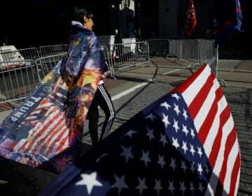 A woman wears a Trump flag as a cape as supporters of President Donald Trump protest outside the Pennsylvania Convention Center, where vote counting continues, in Philadelphia, Monday, Nov. 9, 2020, two days after the 2020 election was called for Democrat Joe Biden. (AP Photo/Rebecca Blackwell)