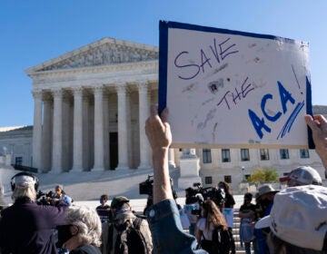 A demonstrator holds a sign in front of the U.S. Supreme Court as arguments are heard about the Affordable Care Act, Tuesday, Nov. 10, 2020, in Washington. (AP Photo/Alex Brandon)