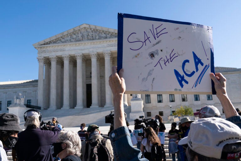 A demonstrator holds a sign in front of the U.S. Supreme Court as arguments are heard about the Affordable Care Act, Tuesday, Nov. 10, 2020, in Washington. (AP Photo/Alex Brandon)