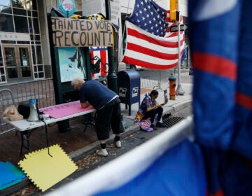 A man makes signs as a handful of supporters of President Donald Trump continue to protest outside the Pennsylvania Convention Center, in Philadelphia, Tuesday, Nov. 10, 2020. (AP Photo/Rebecca Blackwell)